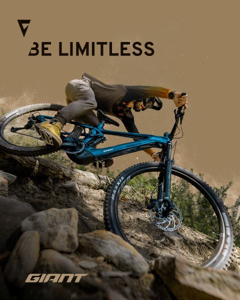 Un cycliste roule à travers un terrain rocailleux sur un VTT bleu. Les mots « Be Limitless » et « Giant » apparaissent sur l'image. Le cycliste porte un casque et des vêtements de cyclisme, ce qui souligne l'aventure et la liberté sur le sentier.