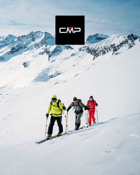 Trois skieurs en tenues colorées gravissent une montagne enneigée sous un ciel bleu clair, entourés de hauts sommets enneigés. Le logo noir « CMP » apparaît en haut au centre de l'image.