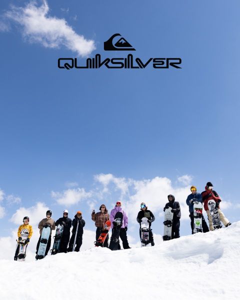 Un surfeur chevauche une grande vague turquoise, incarnant l'équilibre et l'habileté. Il porte un short de bain foncé, et la vague se brise au-dessus de lui. Au-dessus de lui, on peut voir le logo Quiksilver.