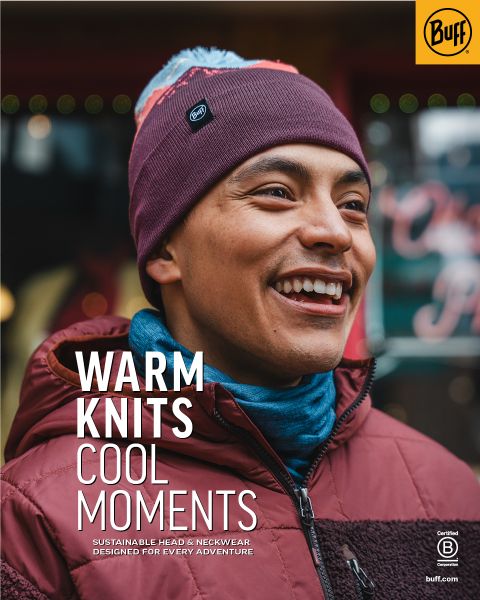 Une personne souriante portant un bonnet en tricot marron et une veste bordeaux se tient à l'extérieur. Le texte sur l'image est : "Tricots chauds, moments cool. Vêtements de tête et de cou durables pour chaque aventure." Logo Buff visible.