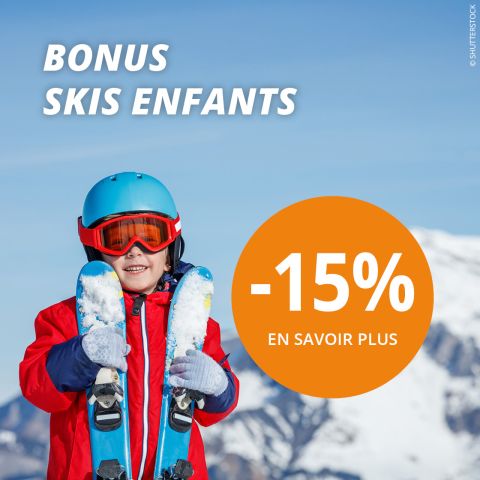 Un enfant en équipement d'hiver rouge et casque bleu tient des skis et sourit devant un paysage de montagne enneigé. Le texte offre 15 % de réduction sur les skis pour enfants, avec "BONUS SKIS ENFANTS" et "EN SAVOIR PLUS" en français.