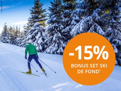 Personne faisant du ski de fond sur une piste enneigée avec des arbres couverts de neige sous un ciel bleu. Un grand cercle orange indique « -15% ENSEMBLE BONUS SKI DE FOND* » en blanc sur le côté droit.
