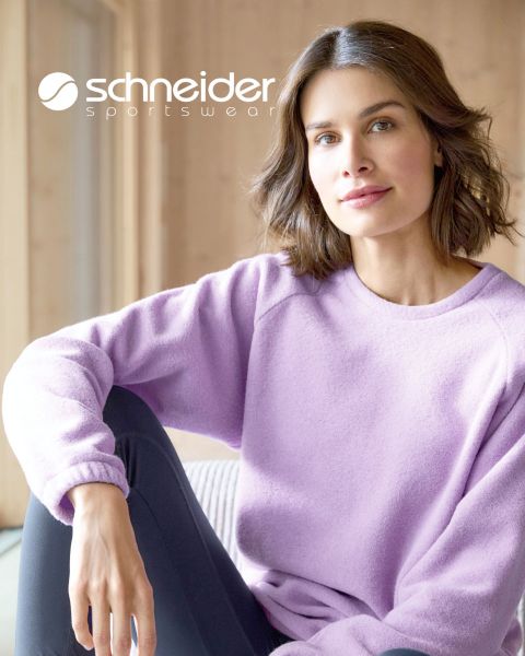 Une personne aux cheveux mi-longs, portant une veste décontractée et un t-shirt, se tient devant un fond neutre. En haut de l'image, on peut lire l'inscription "Schneider Sportswear".