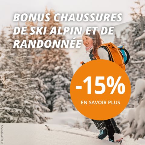 Une personne fait du ski de randonnée en montée à travers une forêt enneigée avec un sac à dos orange. Un texte blanc en français fait la promotion d'un bonus sur les chaussures de ski et de randonnée. Un cercle orange indique "-15% EN SAVOIR PLUS". Des arbres enneigés remplissent l'arrière-plan.