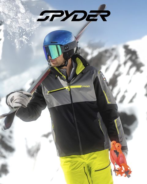 Un skieur en tenue noire et jaune dévale une pente enneigée, avec un paysage enneigé en arrière-plan. En haut, le texte indique : « SPYDER POUR LES SKIEURS DEPUIS 1978 ». Un petit logo d'araignée blanche est visible dans le coin inférieur droit.
