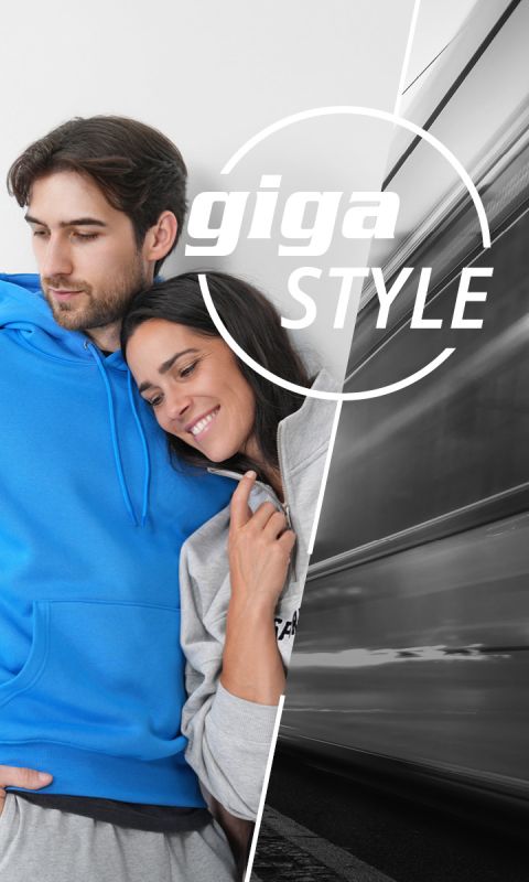 Un homme en sweat à capuche bleu et une femme en sweat à capuche gris s'embrassent en souriant ; l'image est superposée par un train flou sur la droite et les mots en gras "giga STYLE".