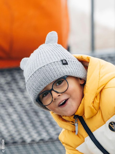 Un enfant portant des lunettes et une veste jaune.