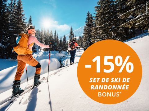 Deux randonneurs à ski gravissent des montagnes enneigées avec des pins ; le cercle orange fait la promotion de "-15% set de ski de randonnée bonus*" en français.
