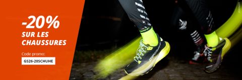 Coureur portant des chaussures et des chaussettes jaune vif lors d'une course de nuit, avec une bannière orange offrant 20 % de réduction sur les chaussures avec le code promotionnel GS26-20SCHUHE.