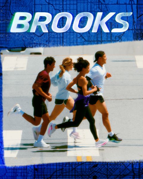Un groupe de cinq personnes traverse énergiquement un passage piéton. Ils portent des vêtements de sport colorés, notamment des shorts et des débardeurs. La scène est animée, et le mot « BROOKS » est bien visible au-dessus d'eux.