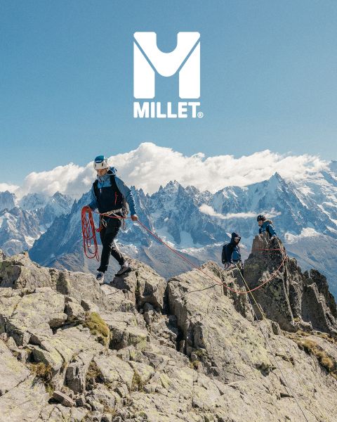 Trois randonneurs en équipement complet marchent à travers un paysage de montagne avec des sommets enneigés. En bas, on peut voir une femme en veste qui ajuste son col. Des montagnes sont visibles en arrière-plan. En bas à droite, on peut voir le logo "Millet".