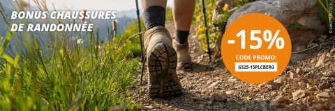 Une personne fait de la randonnée sur un sentier de montagne rocailleux avec un sommet enneigé en arrière-plan. Le texte offre une réduction de 15 % sur les chaussures de randonnée avec le code promotionnel « GS25-15PLCBERG ».