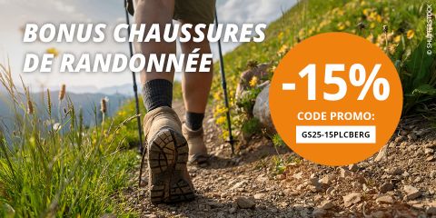 Une femme fait de la randonnée sur un sentier de montagne rocheux avec des sommets enneigés en arrière-plan. Le texte est le suivant : "Bonus chaussures de randonnée -15%. Code promo : GS25-15PLCBERG".