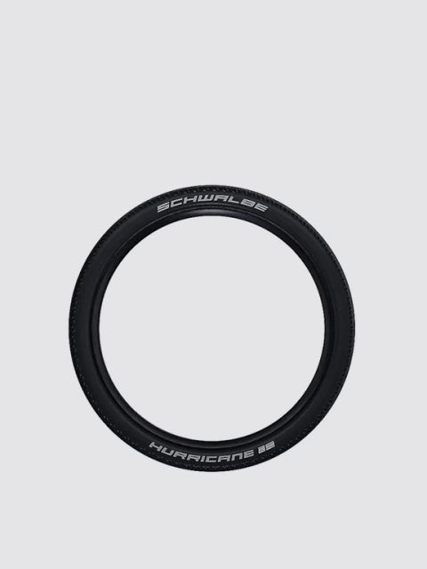 Un pneu de vélo Schwalbe Hurricane noir avec des inscriptions blanches sur un fond gris clair uni.