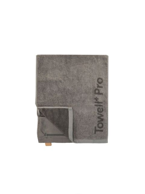Serviette grise pliée avec le texte "Towel Pro", une petite poche zippée et une boucle marron sur un fond blanc uni.