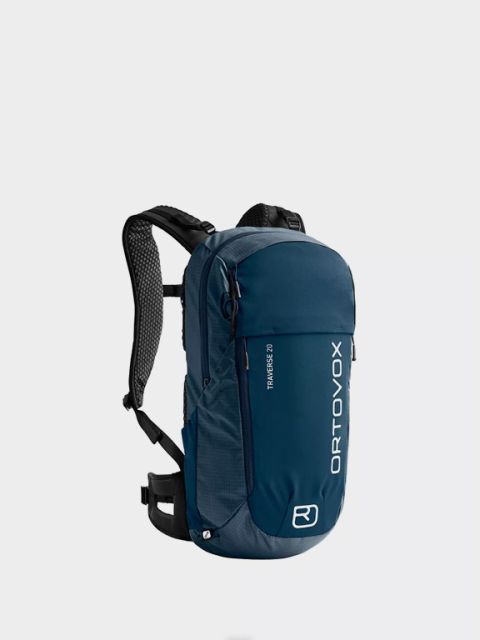 Sac à dos Ortovox bleu avec l'inscription "Rucksäcke" au-dessus. Il est doté de plusieurs fermetures éclair, de sangles réglables et de détails orange sur les curseurs de fermeture éclair et les clips. Le nom de la marque est imprimé verticalement en blanc.