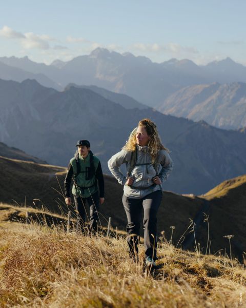 Deux personnes sont visibles sur des photos séparées. La photo de gauche montre une personne en tenue de randonnée avec des bâtons de trekking, celle de droite une autre personne avec un sac à dos et une veste. L'arrière-plan est une structure en bois avec de la mousse. Le texte est « Amateur de plein air Randonneur plaisir ».