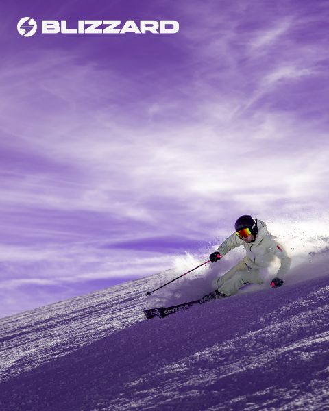 Deux skieurs en tenue d'hiver dévalent une pente enneigée. Le skieur de gauche porte une tenue rose, celui de droite une tenue beige. Les deux portent des casques et des lunettes de protection. Le logo Blizzard est visible en haut à gauche.