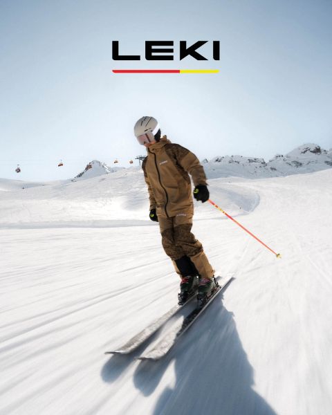 Un skieur en veste jaune et lunettes de ski descend une pente de montagne enneigée avec des bâtons. En arrière-plan, on aperçoit des montagnes enneigées et un lac. Le texte est « QUEL EST TON TERRAIN DE JEU ? SPITFIRE 3D » avec un bouton « DÉCOUVRIR MAINTENANT ».