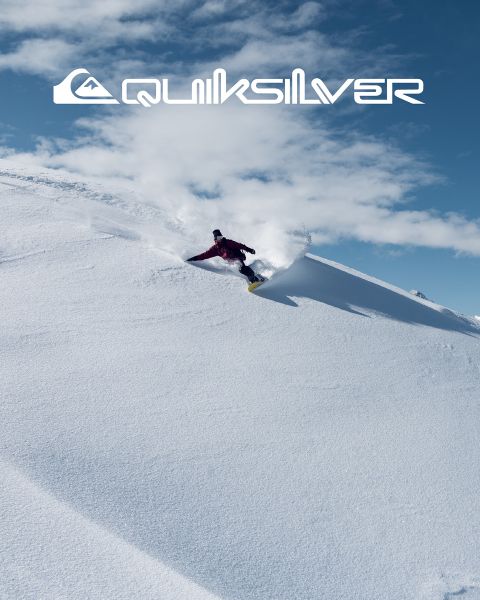 Un surfeur chevauche une grande vague turquoise, incarnant l'équilibre et l'habileté. Il porte un short de bain foncé, et la vague se brise au-dessus de lui. Au-dessus de lui, on peut voir le logo Quiksilver.